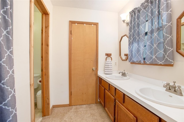 bathroom with double vanity, toilet, and a sink