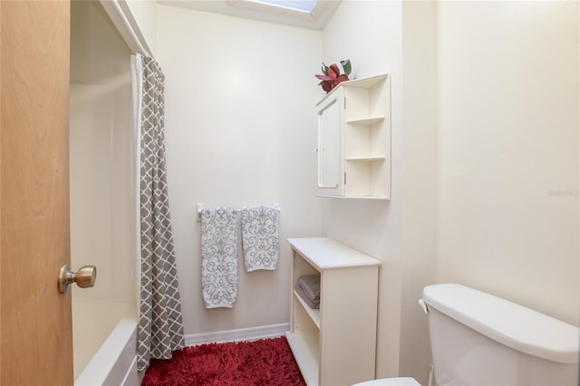 bathroom with a skylight, toilet, and baseboards