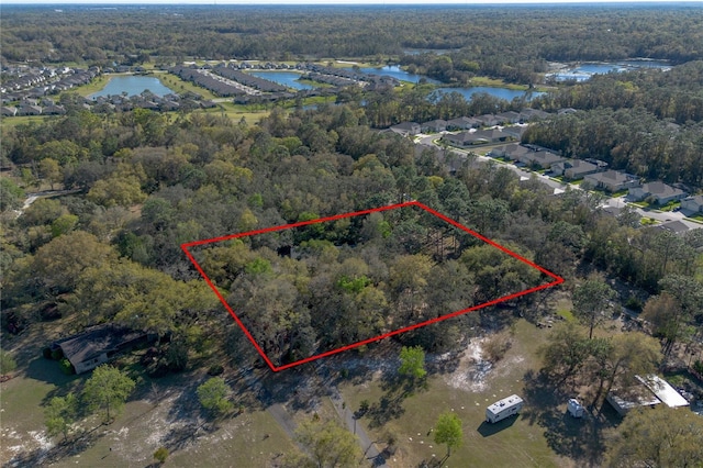 drone / aerial view featuring a wooded view and a water view