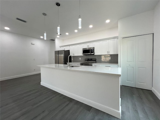 kitchen with tasteful backsplash, appliances with stainless steel finishes, a large island, white cabinetry, and a sink