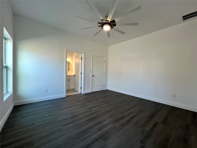 unfurnished bedroom featuring dark wood-style floors, visible vents, ensuite bathroom, and baseboards