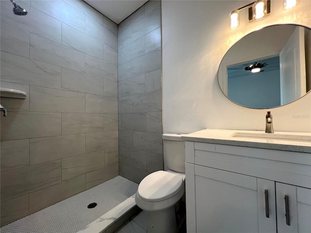 full bathroom featuring vanity, toilet, and tiled shower