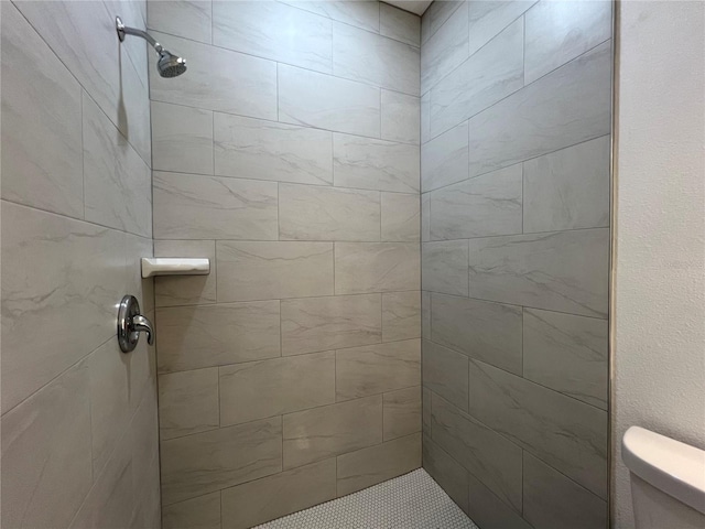 bathroom featuring toilet and a tile shower