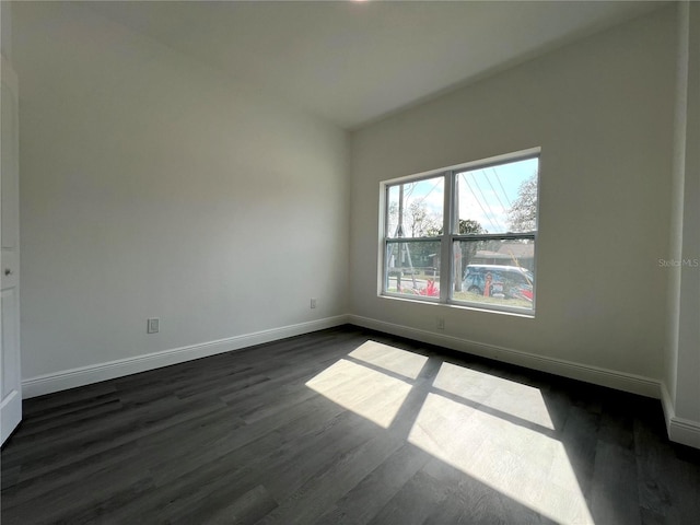 empty room featuring dark wood-type flooring and baseboards