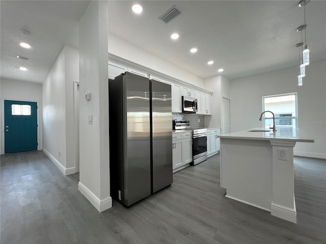 kitchen featuring visible vents, backsplash, appliances with stainless steel finishes, white cabinetry, and a sink