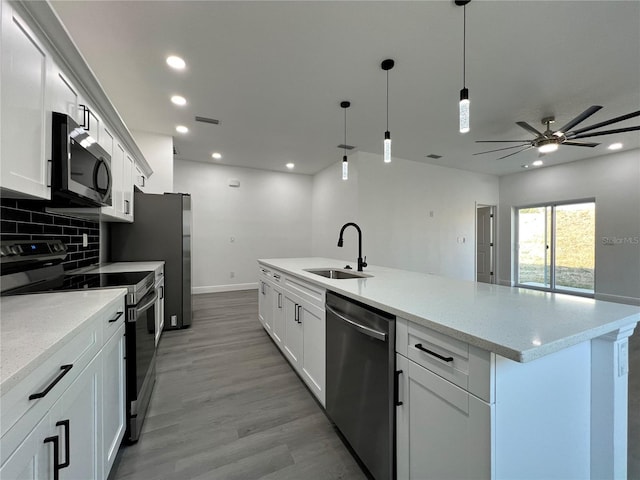 kitchen featuring visible vents, light wood-style flooring, a sink, tasteful backsplash, and appliances with stainless steel finishes