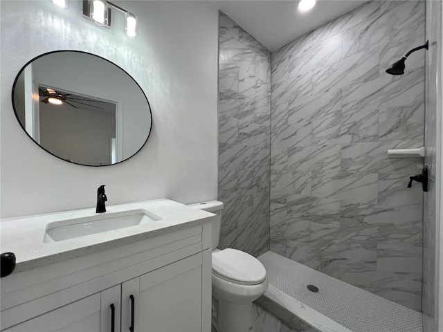 full bath featuring a tile shower, marble finish floor, toilet, and vanity