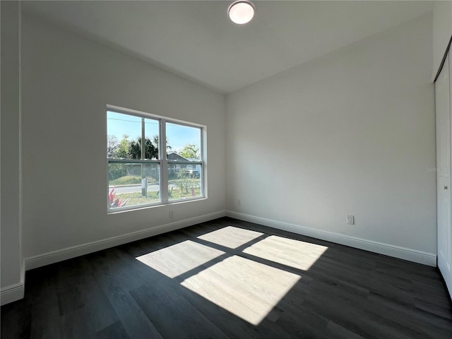 unfurnished room featuring baseboards and dark wood-style floors