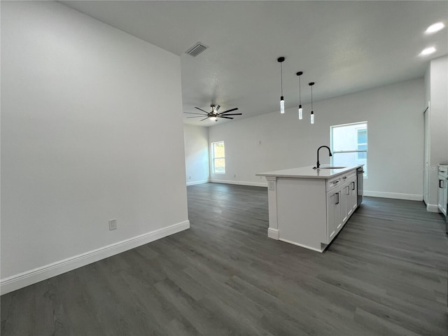 kitchen featuring visible vents, dark wood-type flooring, a kitchen island with sink, open floor plan, and baseboards