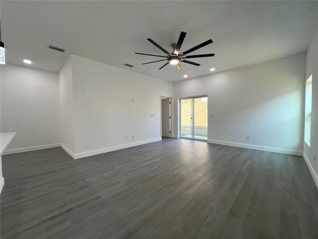 spare room featuring visible vents, baseboards, and dark wood-type flooring