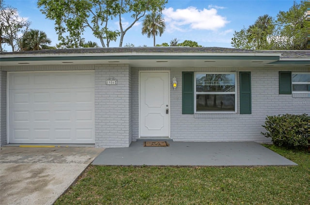 property entrance with an attached garage, brick siding, and driveway