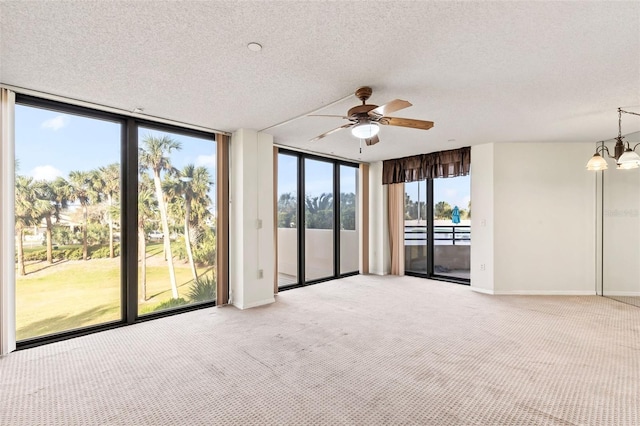 spare room featuring a textured ceiling, floor to ceiling windows, baseboards, and light carpet