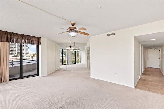 spare room featuring light carpet, visible vents, plenty of natural light, and a textured ceiling