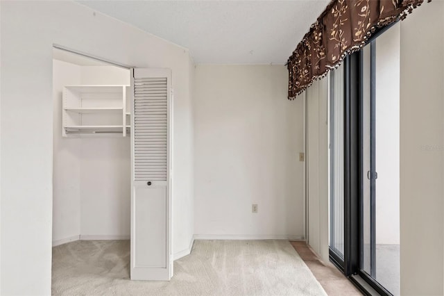 unfurnished bedroom featuring light colored carpet, a closet, and baseboards