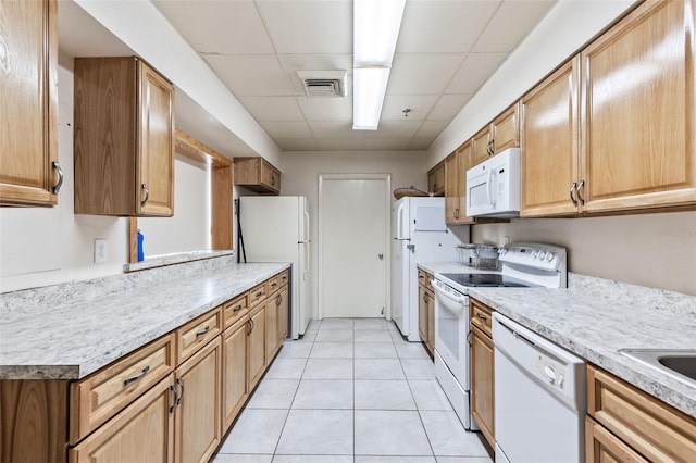 kitchen with white appliances, light tile patterned floors, a paneled ceiling, and light countertops