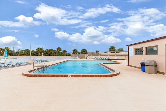 community pool with a patio and fence