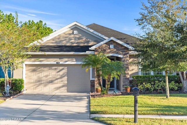 view of front facade with driveway, stone siding, roof with shingles, a front yard, and an attached garage