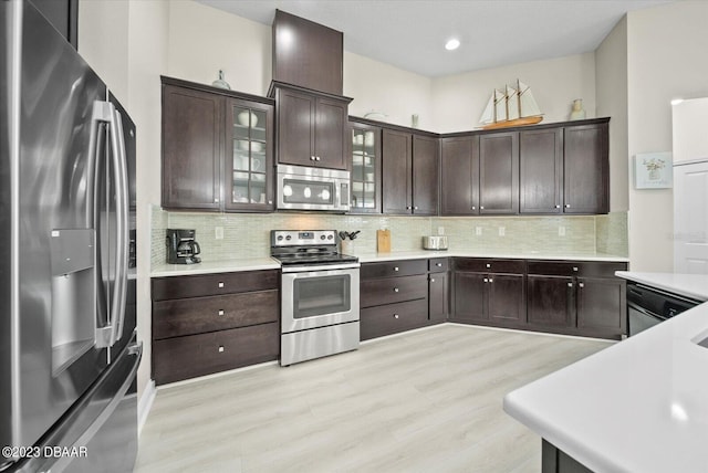 kitchen featuring decorative backsplash, light countertops, dark brown cabinets, and stainless steel appliances