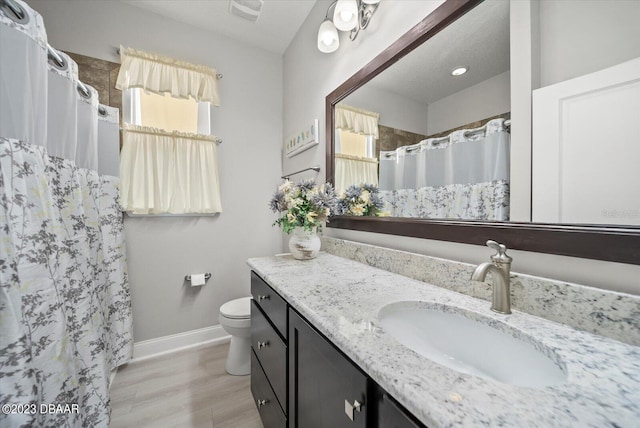 full bath with a shower with curtain, toilet, wood finished floors, baseboards, and vanity