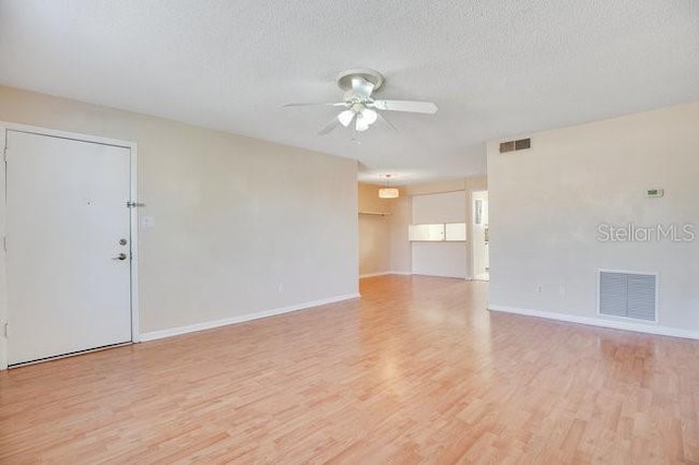 spare room featuring visible vents, a textured ceiling, light wood-style floors, and a ceiling fan