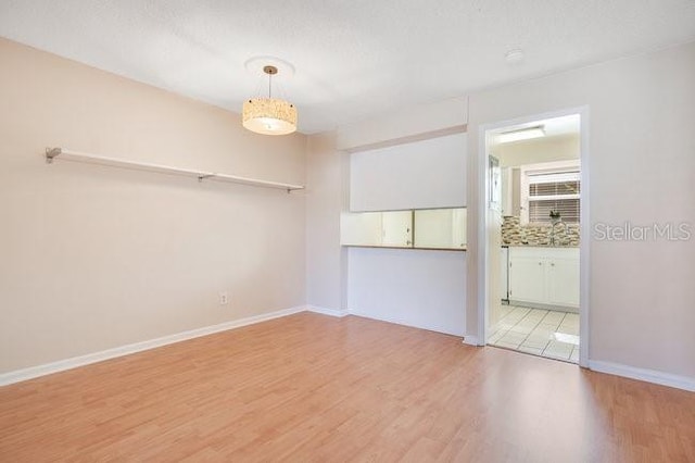 spare room featuring light wood-type flooring and baseboards