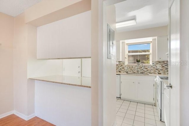 kitchen featuring a sink, light countertops, white cabinets, stove, and tasteful backsplash