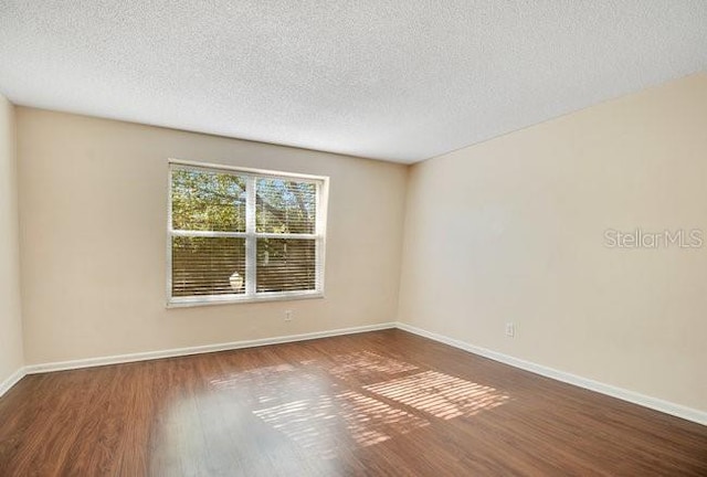 unfurnished room featuring baseboards, a textured ceiling, and wood finished floors