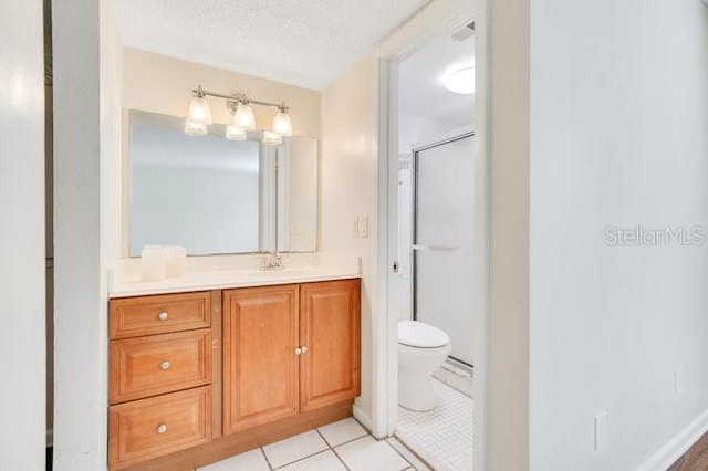 bathroom with a shower stall, toilet, vanity, tile patterned floors, and a textured ceiling