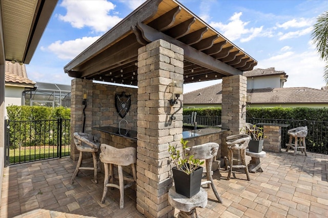 view of patio / terrace featuring a brick fireplace, fence, and outdoor dry bar