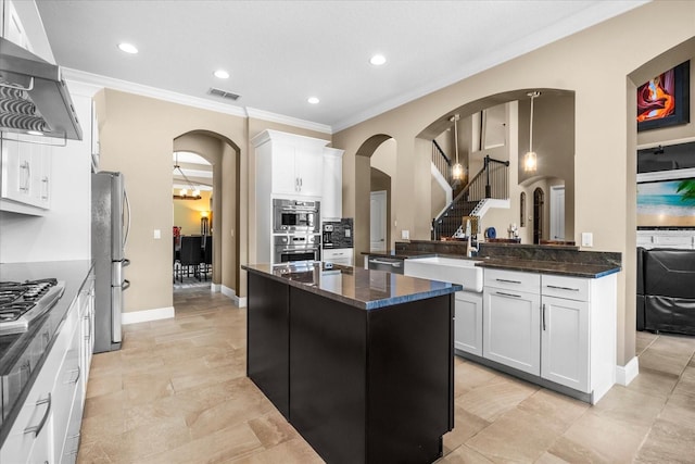 kitchen featuring visible vents, range hood, appliances with stainless steel finishes, arched walkways, and a sink