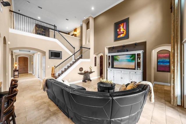 living area featuring visible vents, stairway, arched walkways, baseboards, and a towering ceiling