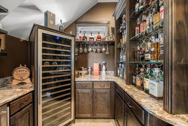 bar featuring a bar, beverage cooler, and vaulted ceiling