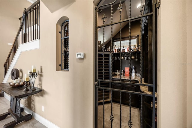 wine room featuring tile patterned flooring, arched walkways, and baseboards