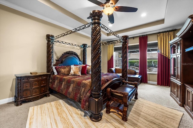 carpeted bedroom with a tray ceiling, baseboards, and a ceiling fan