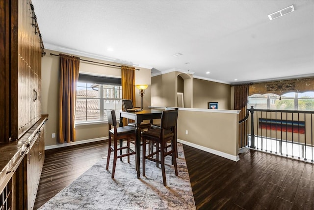 dining room with dark wood finished floors, crown molding, plenty of natural light, and visible vents