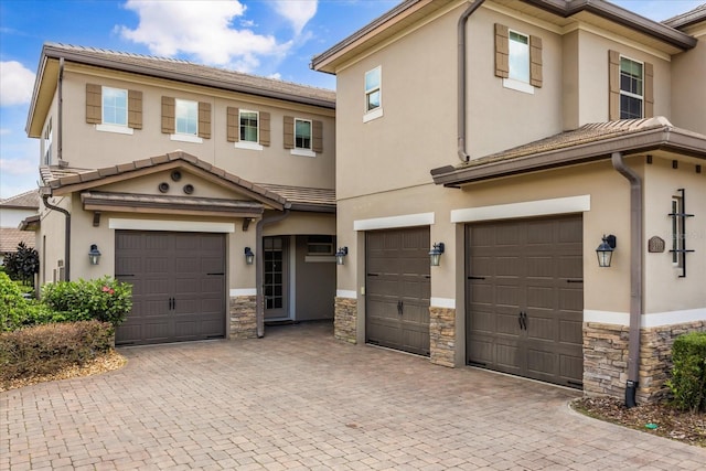 view of front facade featuring a garage, stone siding, and stucco siding