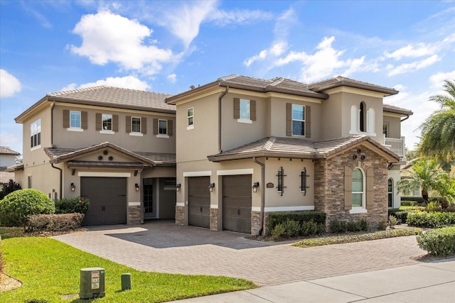 view of front of home with stucco siding, a garage, stone siding, a tiled roof, and decorative driveway