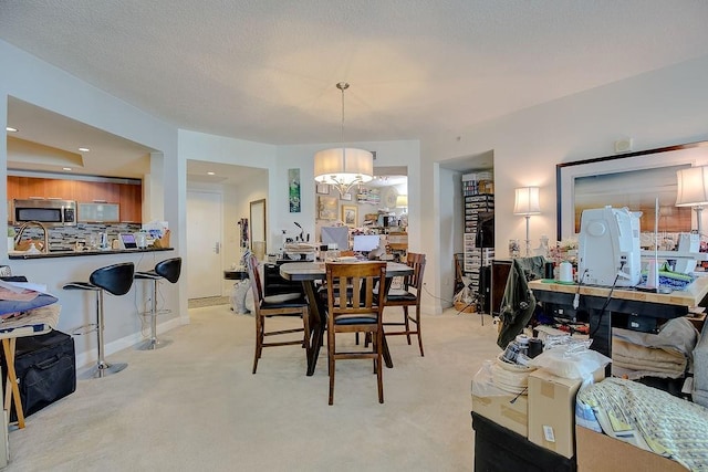 dining space with baseboards, light carpet, and a textured ceiling