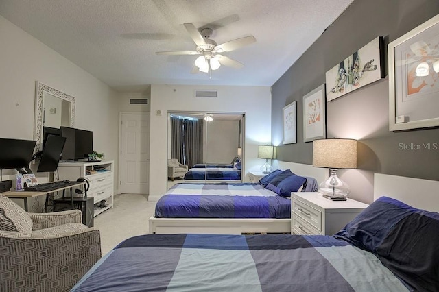 bedroom featuring light carpet, visible vents, a textured ceiling, and ceiling fan