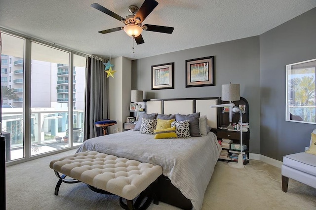 bedroom featuring light carpet, a textured ceiling, access to outside, and expansive windows