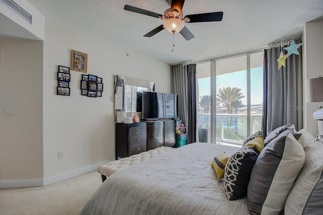 carpeted bedroom with visible vents, a ceiling fan, a textured ceiling, a wall of windows, and baseboards