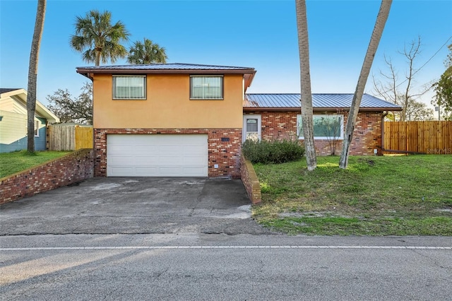 tri-level home featuring a front lawn, driveway, fence, a garage, and brick siding