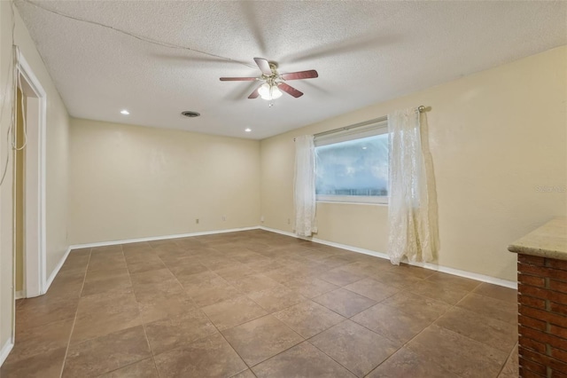 spare room featuring visible vents, a ceiling fan, baseboards, and a textured ceiling