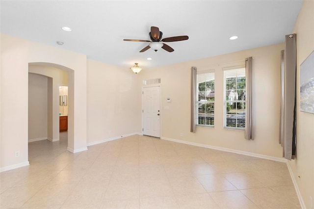 spare room featuring a ceiling fan, recessed lighting, arched walkways, and baseboards