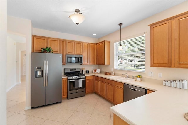 kitchen with decorative light fixtures, light countertops, light tile patterned floors, stainless steel appliances, and a sink