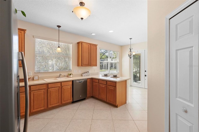 kitchen featuring light countertops, light tile patterned floors, appliances with stainless steel finishes, a peninsula, and a sink