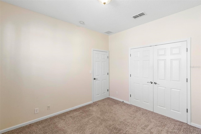 unfurnished bedroom featuring a closet, baseboards, visible vents, and carpet floors