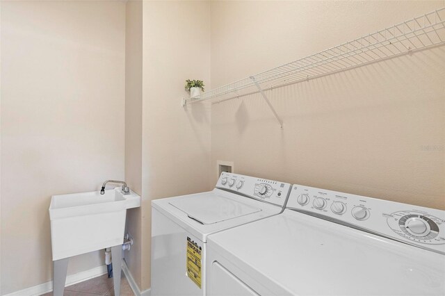 washroom featuring baseboards, laundry area, a sink, tile patterned flooring, and washer and clothes dryer