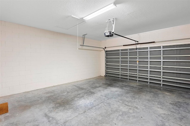 garage with a garage door opener and concrete block wall