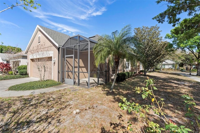 view of front of property with a lanai, concrete driveway, an attached garage, and stucco siding